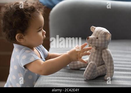 Gros plan adorable tout-petit afro-américaine fille touchant l'ours en peluche Banque D'Images