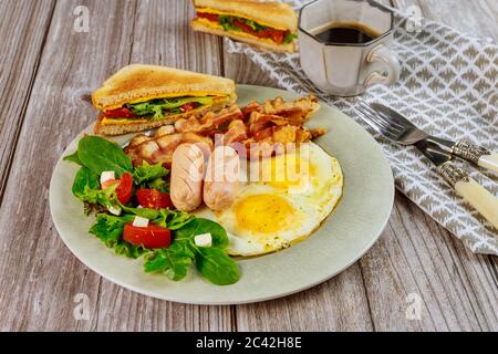 Poulet franks, œufs frits, bacon et salade sur table en bois pour le petit déjeuner. Banque D'Images