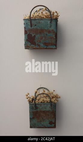 Bouquet de fleurs artificielles fines, de couleur foin, à l'intérieur de deux boîtes en métal bleu, très vieux et rouillé, accroché au mur Banque D'Images