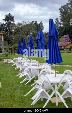 Table et chaises en plastique avec parasols fermés sur chacune Banque D'Images