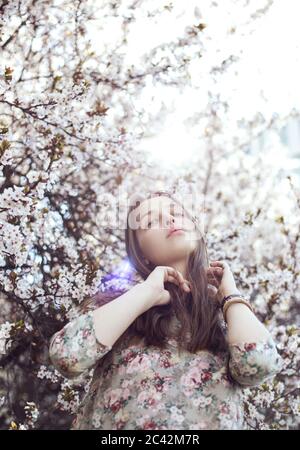 Portrait d'une jeune femme dans un arbre en fleurs au printemps Banque D'Images