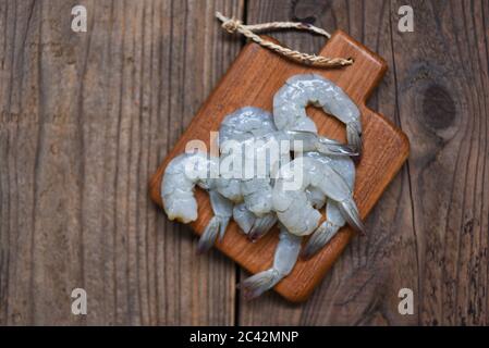 Crevettes fraîches ou crevettes, poisson-fond de fruits de mer pour la cuisson / crevettes crues sur fond de planches à découper en bois Banque D'Images