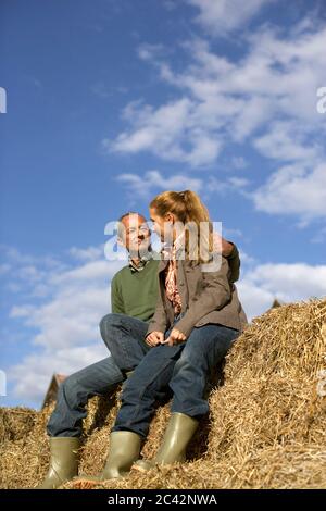 Un couple d'âge moyen est assis sur une pile de balles de paille - partenariat Banque D'Images