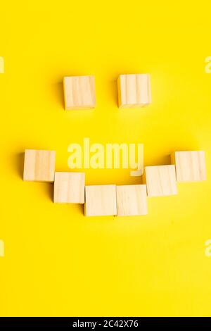 blocs en bois formant un visage souriant sur fond jaune avec espace de copie pour le texte Banque D'Images