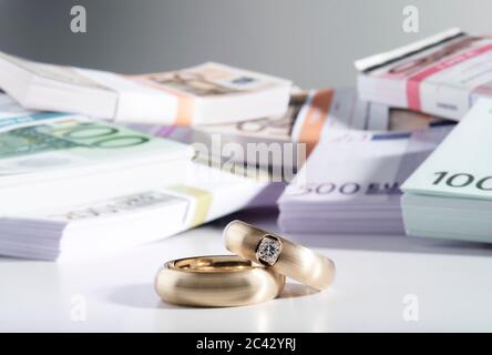 Deux anneaux de mariage et une pile de billets Banque D'Images