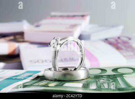 Deux anneaux de mariage et une pile de billets Banque D'Images