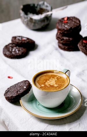 Biscuits maison au chocolat noir et aux brownies salés, décorés de framboises séchées, de flocons de sel et d'une tasse d'espresso sur un pot de table en coton blanc Banque D'Images