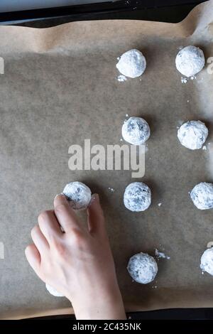 Placer des petits pains de chocolat enrobés de sucre en poudre sur une plaque à pâtisserie. Banque D'Images