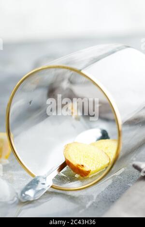 Limonade maison fraîchement préparée avec gingembre et glaçons en verre avec eau claire sur fond de pierre grise. Boisson non alcoolisée d'été froide. Banque D'Images