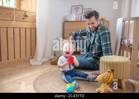 Père dans une chemise à carreaux souriant tandis que son petit fils ne regarde pas satisfait Banque D'Images