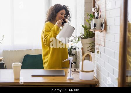 Femme au téléphone dans les usines d'arrosage de bureau à domicile Banque D'Images