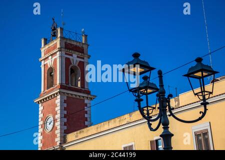 Tour d'horloge, rouge avec briques blanches. Le bâtiment date du XIXe siècle. Lampe de rue en fer à repasser de style Liberty. Cerignola, Puglia, Italie. Banque D'Images