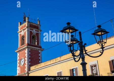 Tour d'horloge, rouge avec briques blanches. Le bâtiment date du XIXe siècle. Lampe de rue en fer à repasser de style Liberty. Cerignola, Puglia, Italie. Banque D'Images