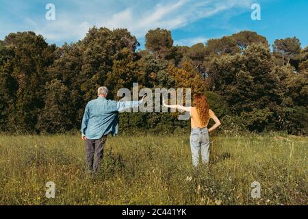 Vue arrière de la femme et de l'homme âgé avec des masques debout sur la prairie, distance de sécurité Banque D'Images