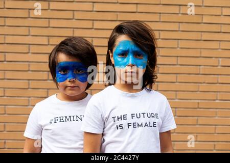 Portrait de deux frères avec masques bleus peints sur leur visage portant des t-shirts avec des empreintes féministes Banque D'Images