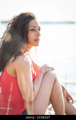 Portrait de la jeune femme assise sur le bord du lac et regardant à distance Banque D'Images