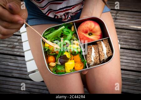 Portrait de jeune fille ayant dîner sain tout en étant assis sur un banc Banque D'Images