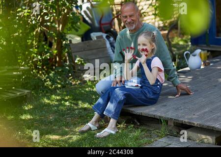 Grand-père et petite-fille aux framboises sur le bout des doigts, assis sur la terrasse dans le jardin Banque D'Images