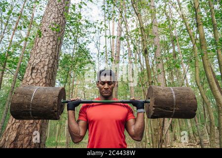 Sportsman s'exerçant avec des cloches en bois dans la forêt Banque D'Images