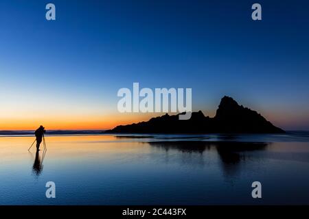 Photographie touristique tout en se tenant à Karekare beach against clear sky pendant le coucher du soleil, Nouvelle-Zélande Banque D'Images