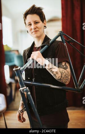 Portrait de femme percée et tatouée avec cadre de vélo sur son épaule Banque D'Images