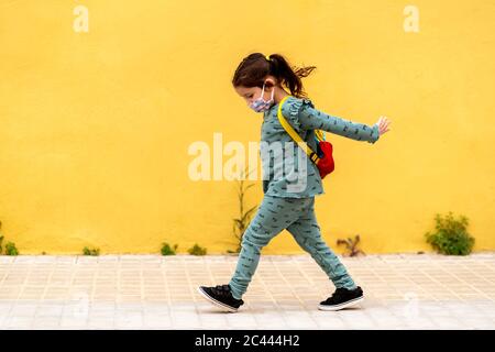 fille marchant avec sac à dos et masque à l'extérieur Banque D'Images
