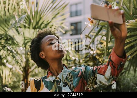 Portrait d'une jeune femme prenant un selfie avec un smartphone dans le jardin Banque D'Images