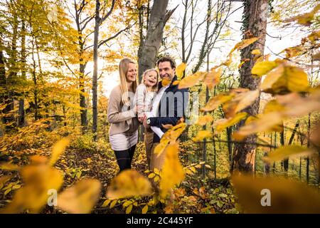 Parents souriants et fille explorant la forêt en automne Banque D'Images