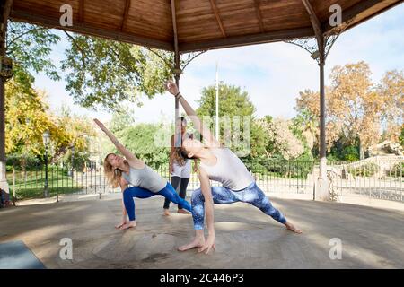 Instructeur de yoga observant l'homme et la femme pratiquant la position de guerrier dans le belvédère au parc de Ciutadella Banque D'Images