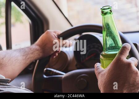 Un homme méconnaissable boit de la bière en conduisant. Concepts de conduite sous influence, conduite en état d'ivresse ou conduite avec facultés affaiblies Banque D'Images