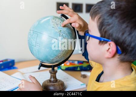 Étudiant explorant sur le globe pendant le homeschooling Banque D'Images