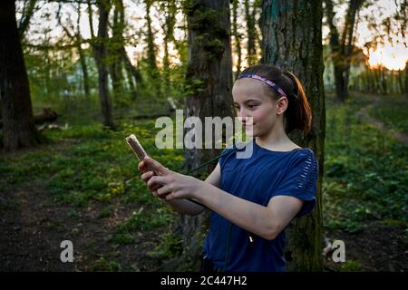 Fille prenant selfie avec un smartphone en forêt Banque D'Images