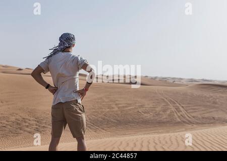 Jeune touriste mâle debout sur des dunes de sable dans le désert à Dubaï, Émirats arabes Unis Banque D'Images