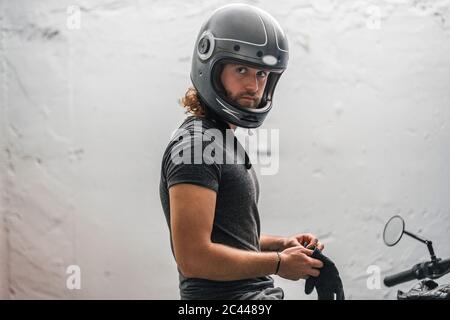 Jeune homme mettant ses gants assis sur la moto Banque D'Images