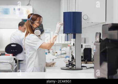 Une femme qui utilise des équipements médicaux tandis qu'une collègue de sexe masculin travaille en laboratoire Banque D'Images