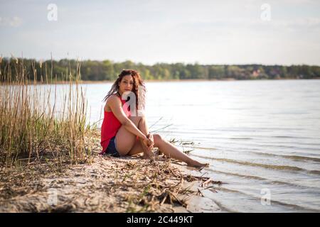 Portrait de la jeune femme assise sur le bord du lac Banque D'Images