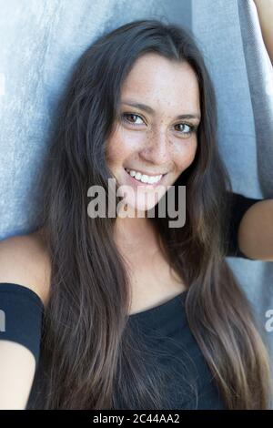 Portrait en gros plan d'une jeune femme souriante, à l'image d'une femme, contre un rideau à la maison Banque D'Images