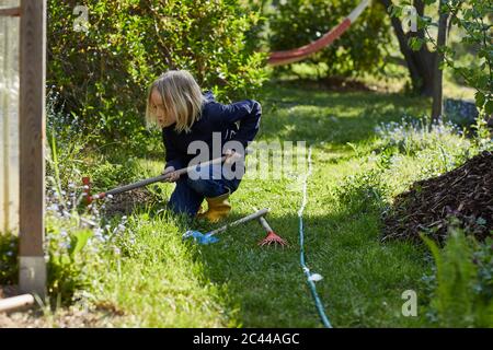 Fille travaillant avec une houe dans le jardin d'allotement Banque D'Images