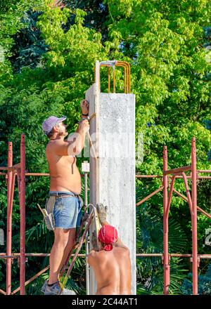 L'ouvrier verse du ciment dans les coffrages de piliers dans la zone de construction du chantier. Banque D'Images