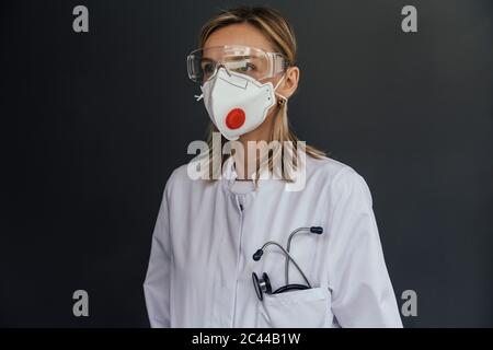 Portrait d'un médecin portant un masque FFP3 et des lunettes de sécurité sur fond gris Banque D'Images