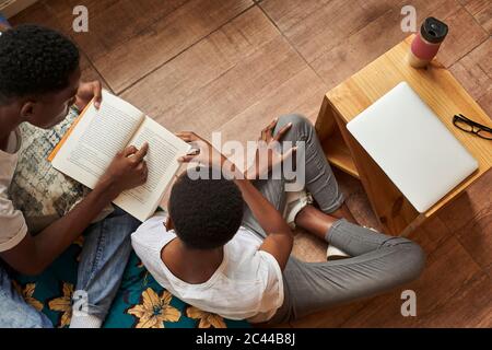 Vue de dessus de jeune couple lisant le livre à la maison ensemble Banque D'Images