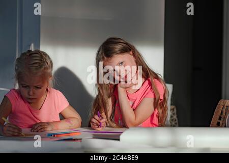 Bonne fille assise avec la couleur de soeur sur le papier à la maison Banque D'Images