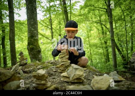 Garçon empilant des pierres comme cairn dans la forêt du Jura souabe Banque D'Images