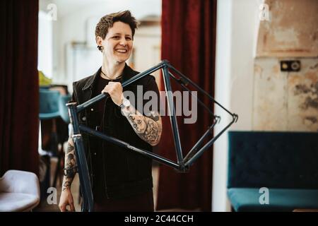 Portrait de femme percée et tatouée avec cadre de vélo sur son épaule Banque D'Images