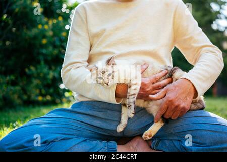 Homme âgé qui se câline avec son chat dans le jardin Banque D'Images