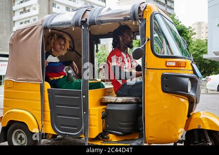 Jeune femme voyageant à travers tuk-tuk en ville Banque D'Images