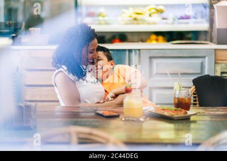 Jeune femme qui apprécie son enfant au restaurant Banque D'Images