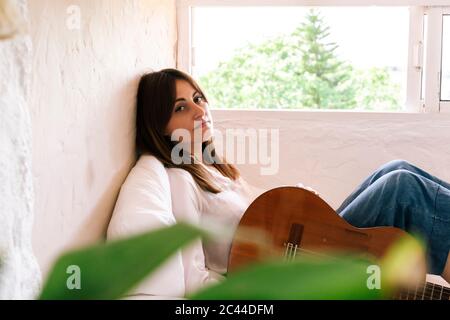Portrait de femme avec guitare assis sur le lit relaxant Banque D'Images