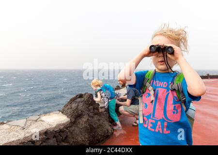 Curieux garçon regardant à travers des jumelles tout en appréciant en vacances avec la famille à Costa Adeje, îles Canaries, Espagne Banque D'Images