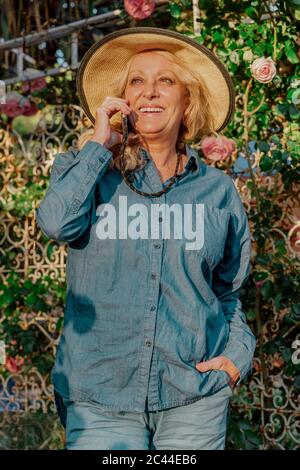 Portrait d'une femme âgée heureuse au téléphone dans son jardin Banque D'Images